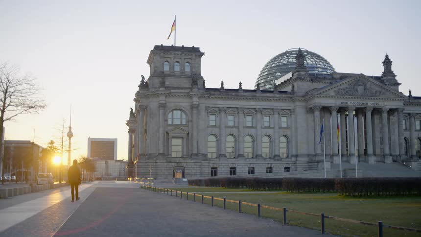 A man walks past a capitol building at sun rise