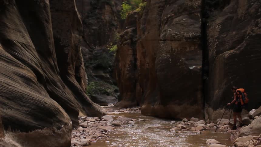 A hiker walks next to a stream in the wilderness