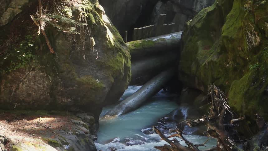 A stream of fresh water flows through a dam in a rocky opening