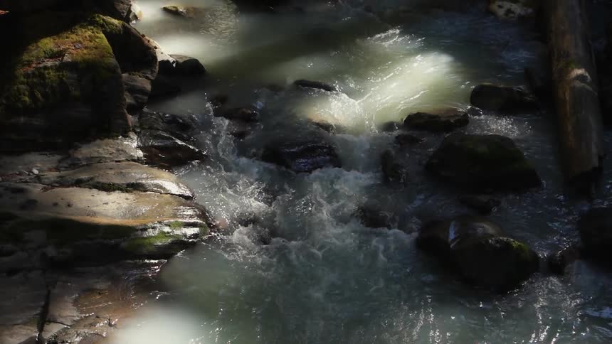 Muddy water flowing swiftly in a rocky stream bed