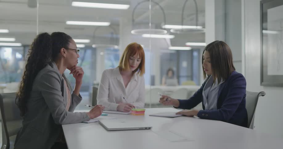 Businesswomen sitting at the table with laptop talk to each other in the office