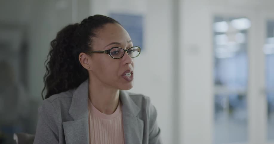 A woman in an office setting sits and talks