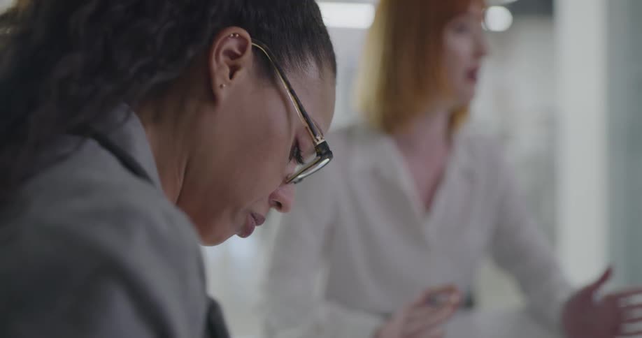 Two women in an office setting on is talking and the other just listens