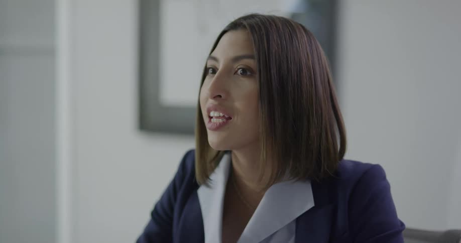 A woman sitting and talking in an office then writing on a pad