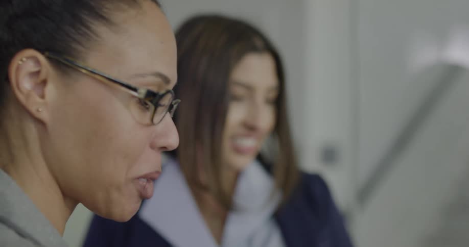 Three women in an office talk together and then high five one another