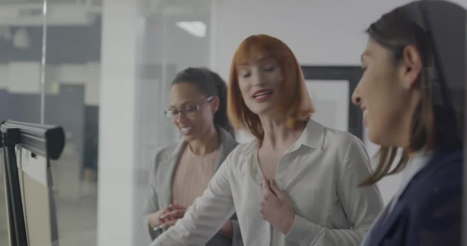 A group of women talk in a conference room and high five one another