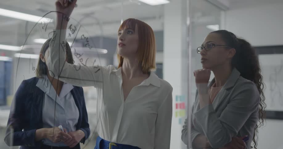 Three women brainstorm in an office together
