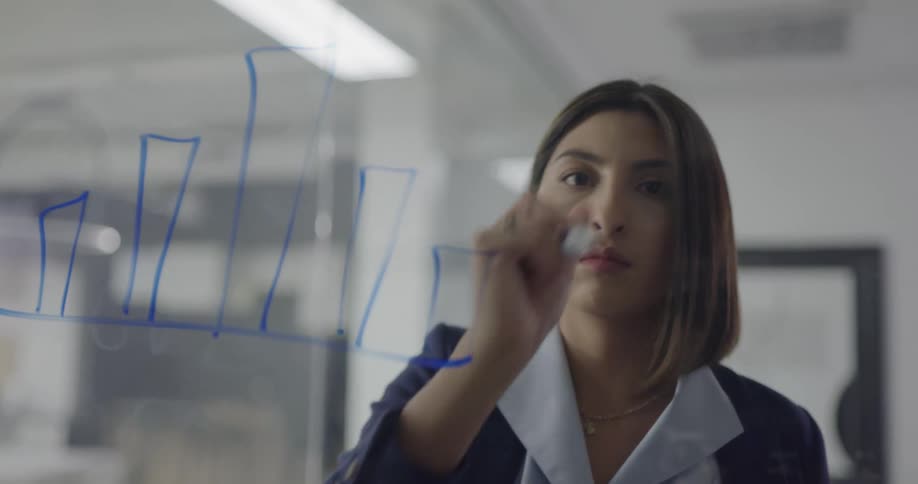 A woman in an office draws on a dry erase board