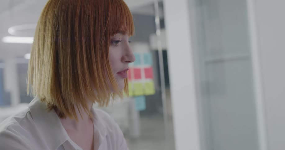 A woman with red hair sits in an office working