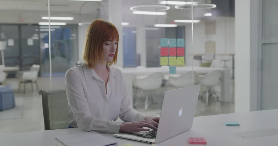 A woman types on her laptop in an office