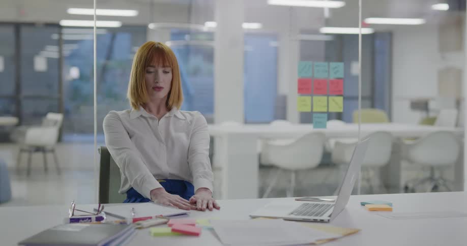 A woman sitting in an office typing on a laptop