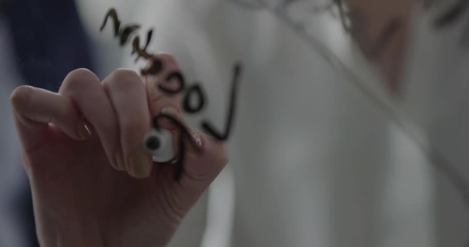 A woman writes on a dry erase board as another woman watches