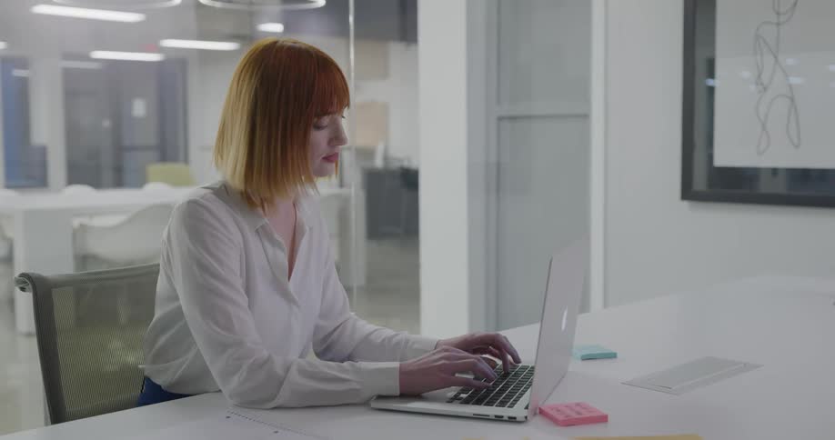 A woman types on a laptop in an office