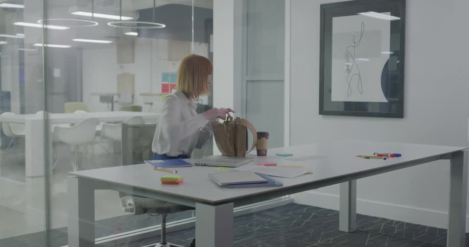 Businesswoman puts the laptop on the table and sits down in the office