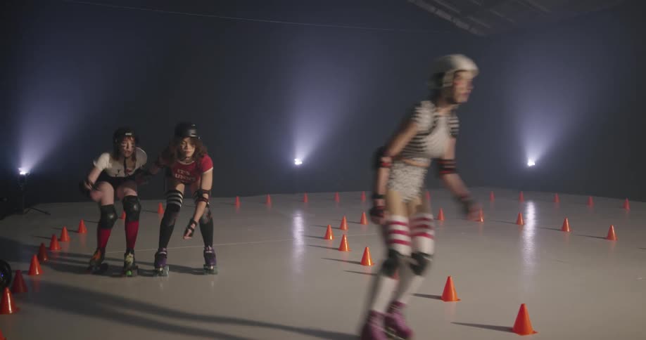 Four women skate around cones