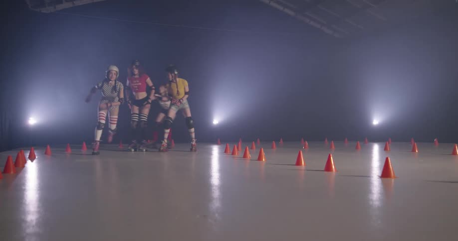Two women race around cones as two others slowly skate along