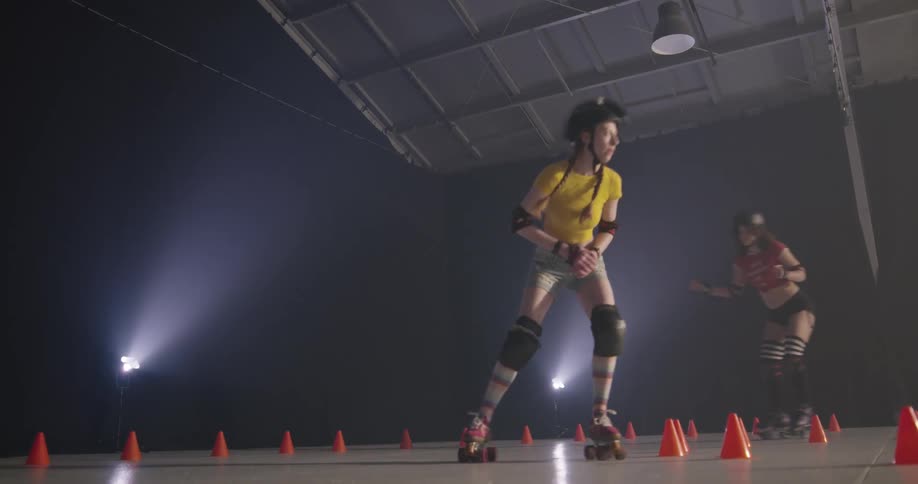 Four women roller skate around cones