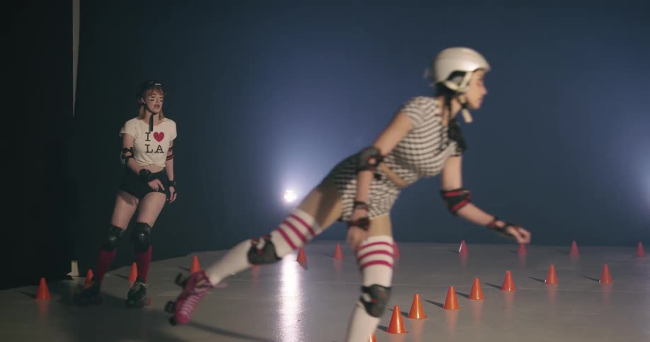 Women wearing helmets roller skating indoors
