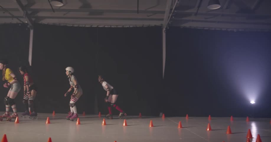 Two girls roller skate around cones as another two girls race past them