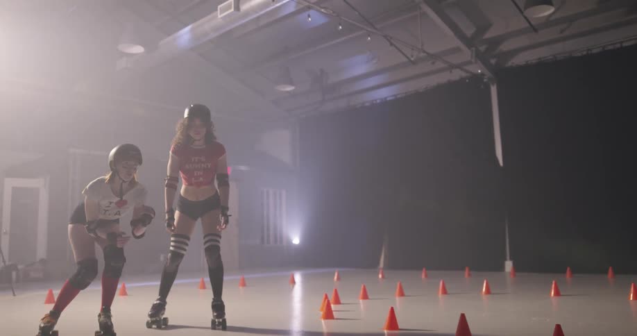 Four teenager roller skate around cones