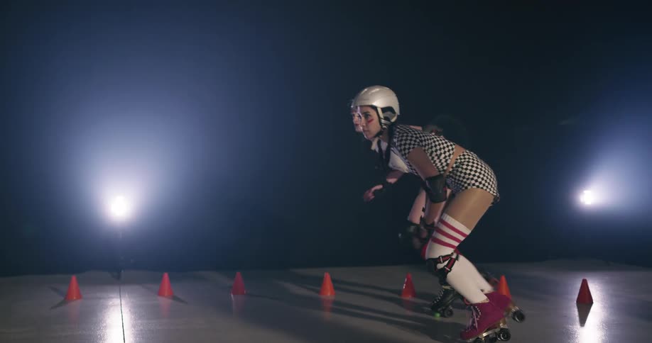 Two women with helmets racing on roller skates