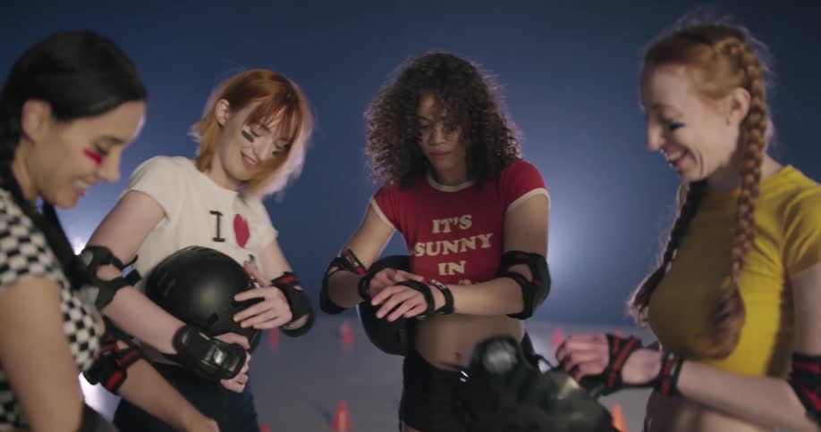 Four women stand in a circle and laugh and remove their helmets