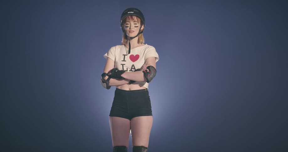 A woman with a helmet and elbow pads standing with her arms crossed