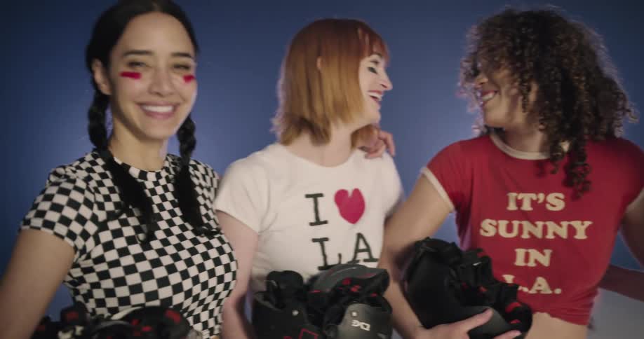 Women wearing roller skate gear laugh and talks