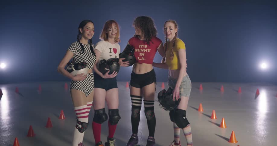 For women holding helmets on roller skates standing laughing and talking