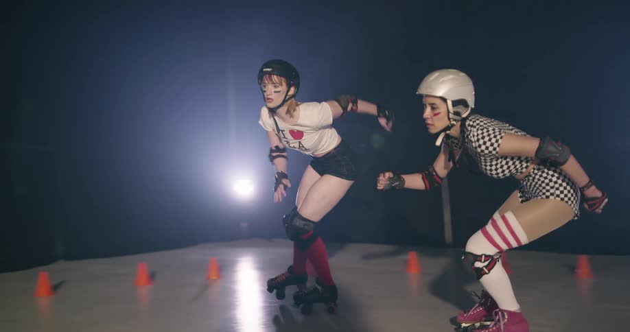 Two women race one another on roller skates