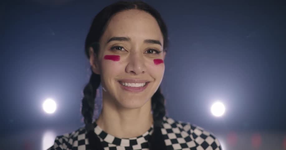 Woman wearing colored eye black smiles at camera