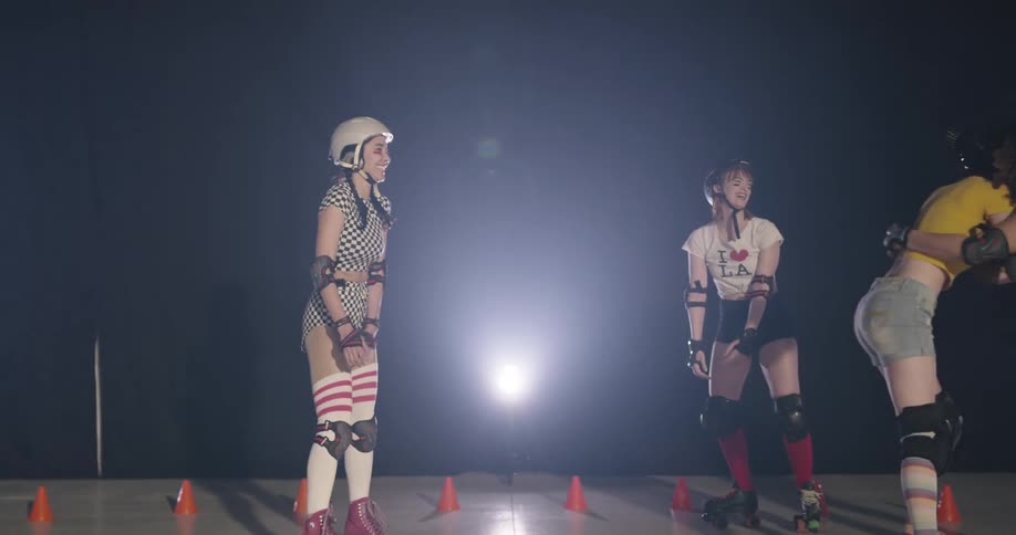 Women in roller skates and protective gear hug and high five one another