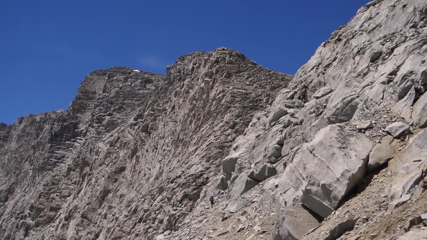 A person hikes on a steep rocky hill