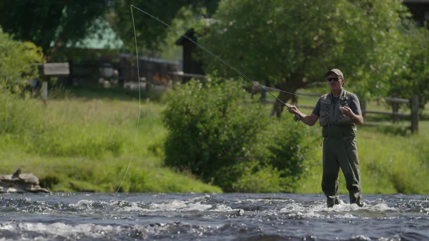 A man is fly fishing on a bright sunny day