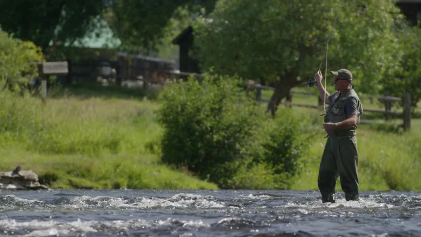 A man fly fishing in a river on a sunny day