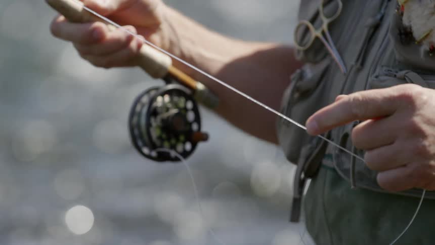 A fisherman standing in the water and reeling in his line