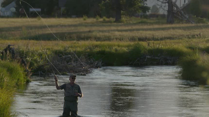 A man stands in a river fly fishing
