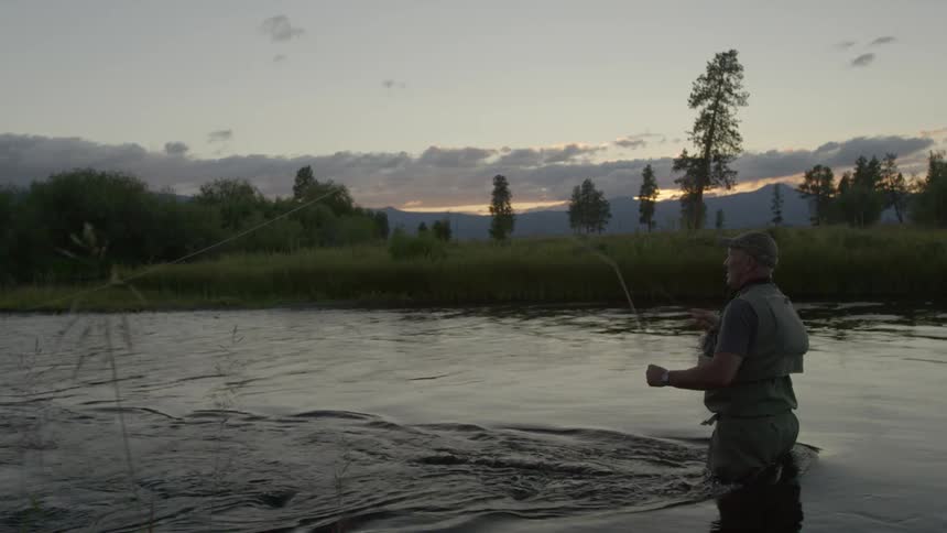 A man stands in a river fly fishing