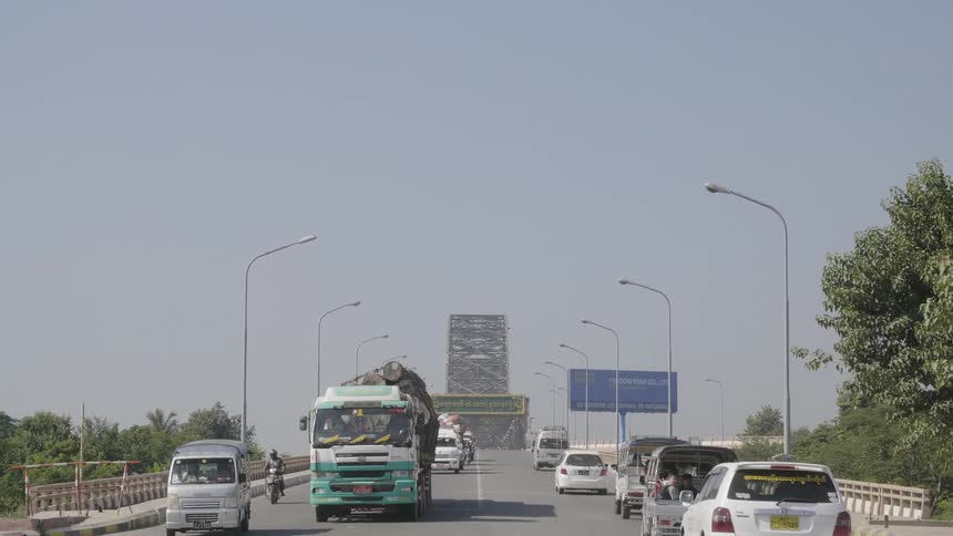 Traffic moves down a road as a pedestrian crosses the street