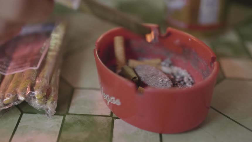 Two white people put cigar ashes into an ashtray