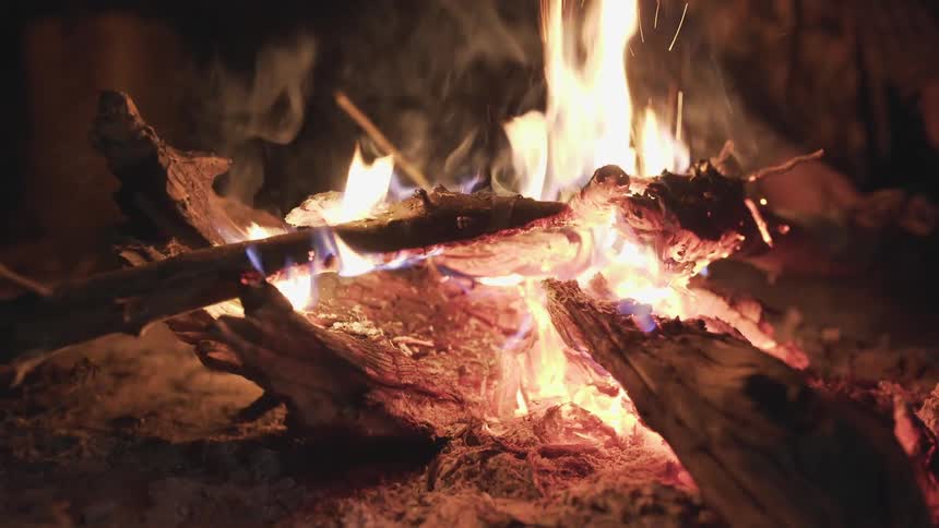 A campfire burning with someone tending to the flame