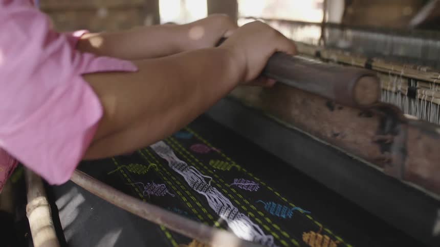 A woman using a machine to make cloth