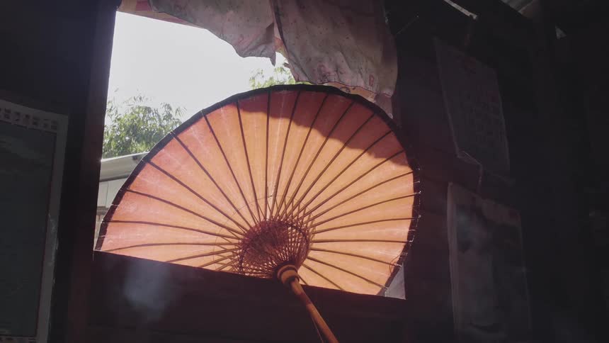 A paper umbrella sits in an open window as smoke rises from below