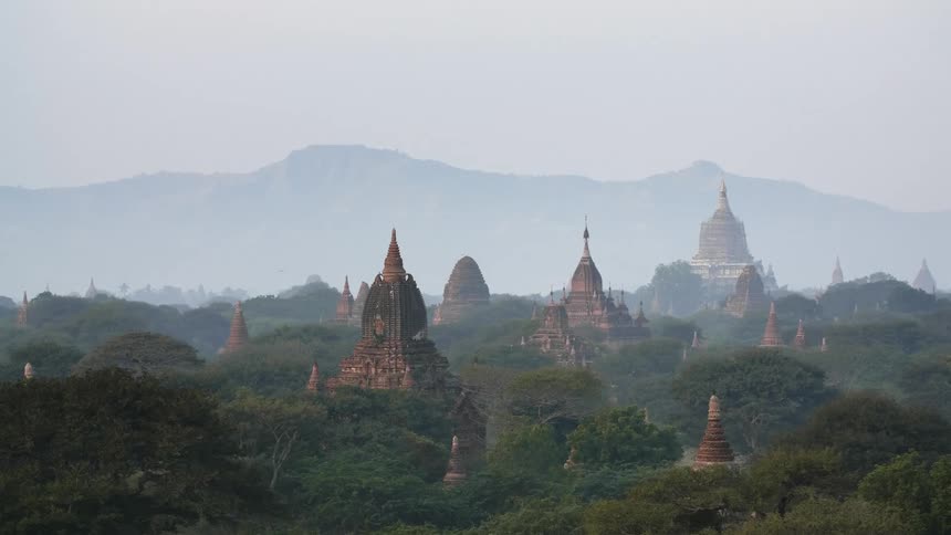 Temples of varying sizes in a third world country sit near a mountain range