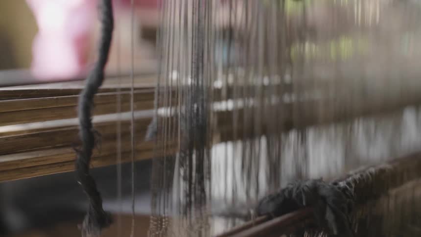 A woman operates a fabric loom