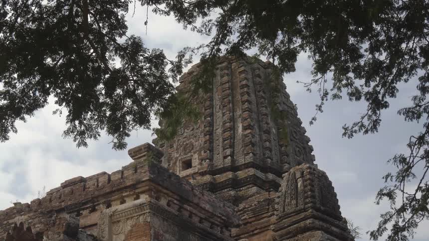 Bird flies from tall ornate asian pagoda under a cloudy sky