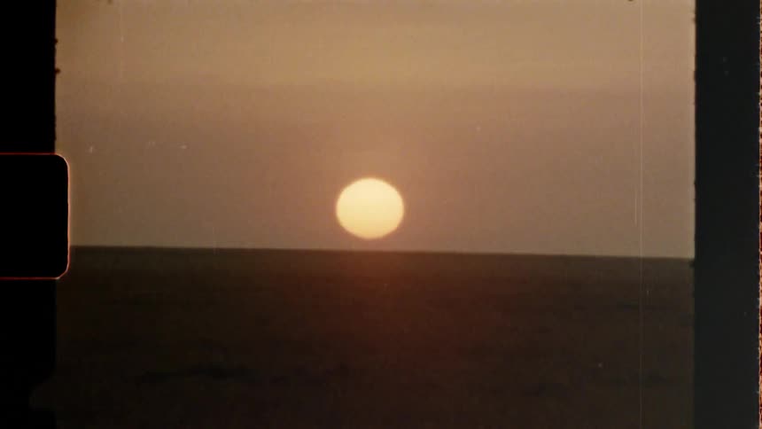 The sun sets over the horizon in vintage film footage
