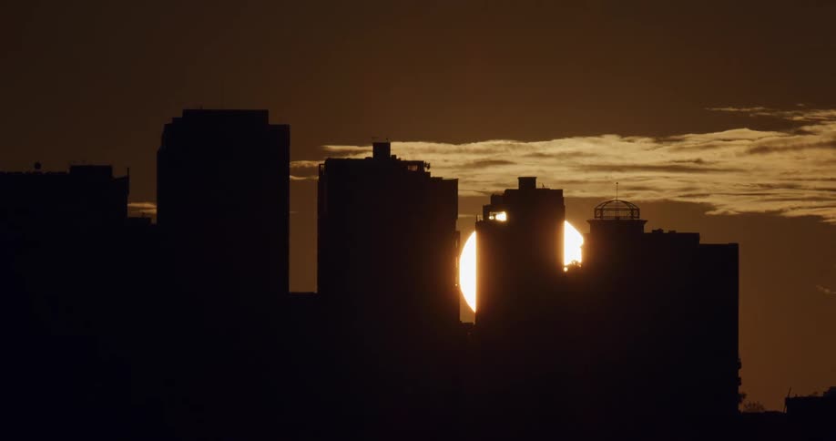 The sun sets behind a city skyline
