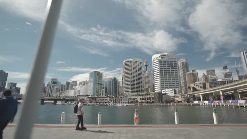Inline skater skates along waterfront across from downtown passing pedestrians
