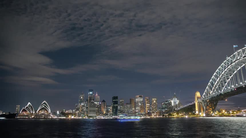 A city skyline with boats and a bridge in the foreground